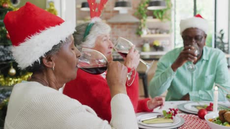 Fröhliche-Gruppe-Verschiedener-älterer-Freunde,-Die-Zur-Weihnachtszeit-Essen-Feiern-Und-Wein-Trinken