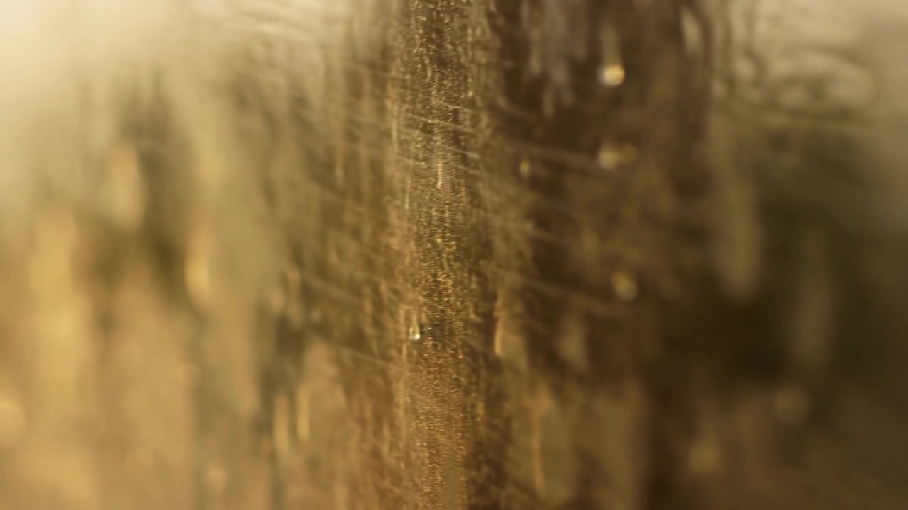 Primer plano extremo de gotas de agua asentándose sobre un panel translúcido rayado, iluminado por una cálida luz de fondo direccional, con textura rayada, desenfoque suave y detalle abstracto luminoso, con gota, agua