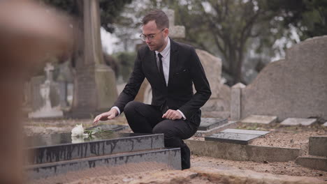 funeral, cemetery and man with flower at tombstone