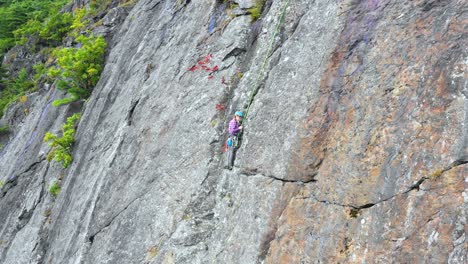 aerial footage close up of young female climber preparing on the side of a cliff in maine