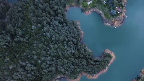 aerial shot of a lake at guatape, tilting up into the landscape