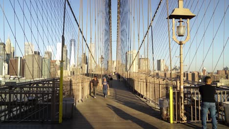 commuters crossing brooklyn bridge in new york on a sunny evening