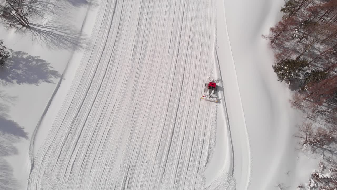 Aerial top view of groomed ski slope with snowcat in winter mountains of Aomori Japan