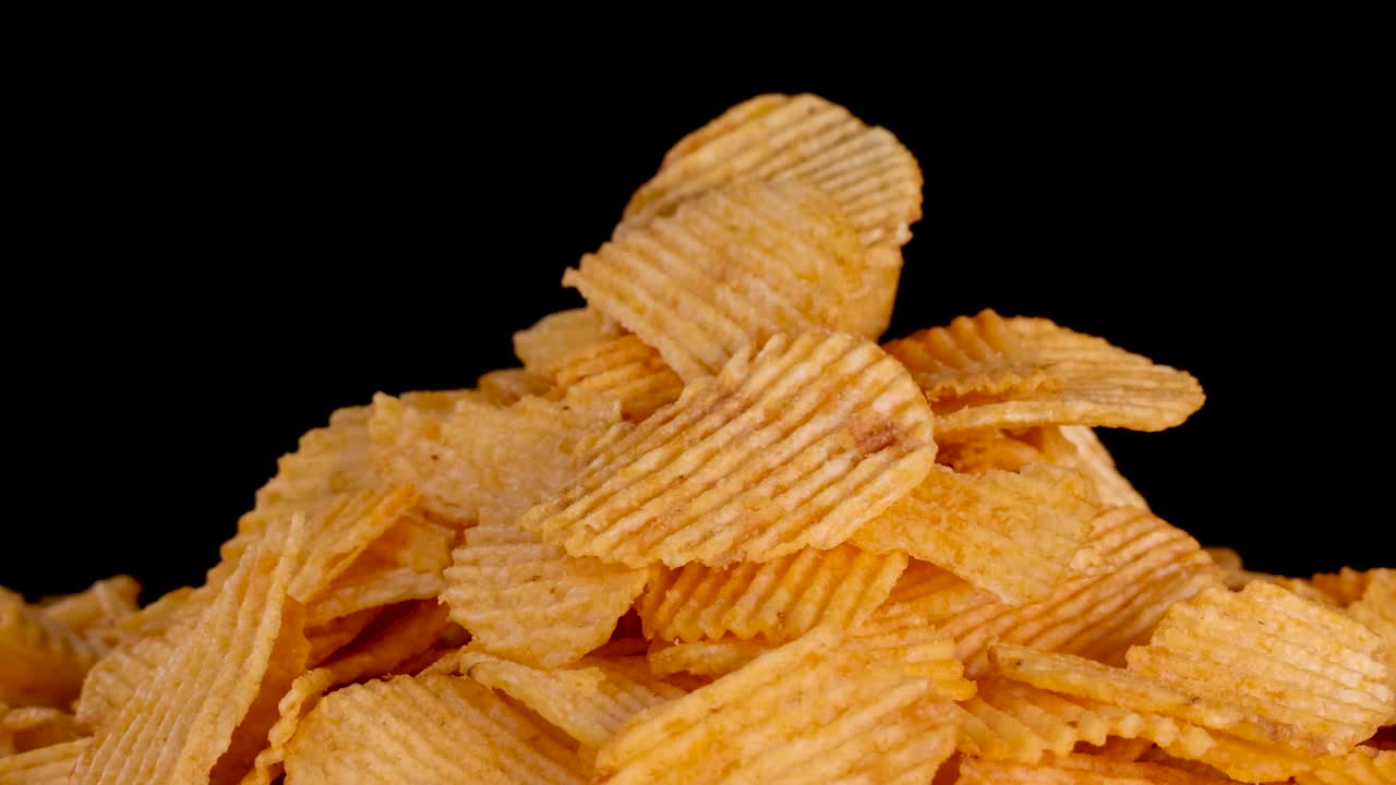 La telecamera esegue uno zoom fluido su patatine fritte dorate su uno sfondo nero uniforme