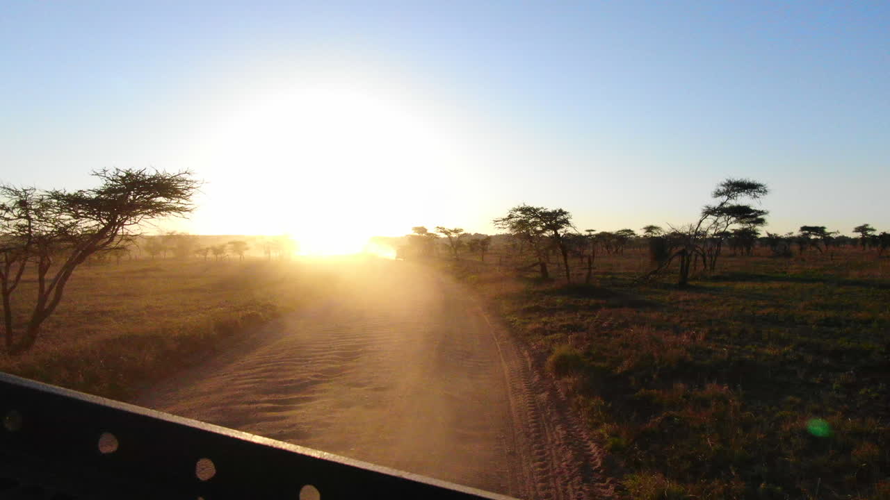 vista de una puesta de sol africana mirando por la parte trasera de un vehículo de safari en el serengeti