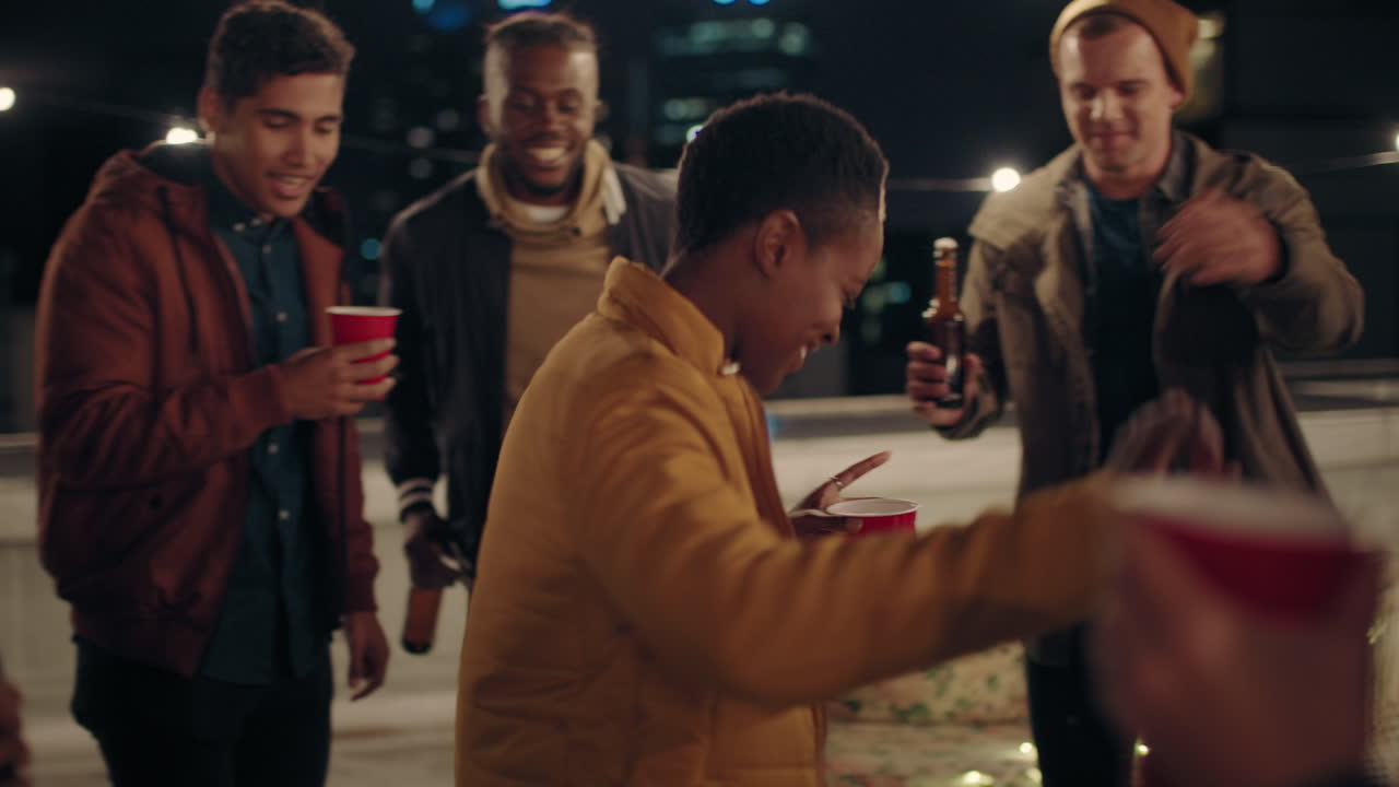 multi ethnic group of friends having fun dancing to music on rooftop at night enjoying celebration party