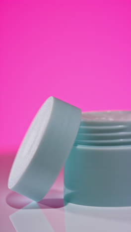 light blue cosmetic jar on pink background