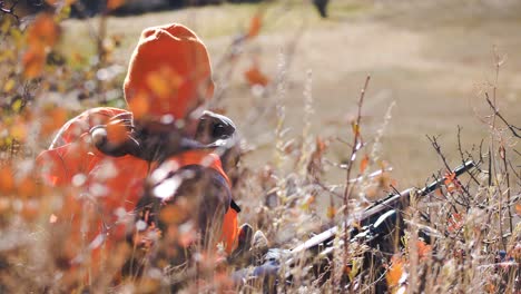 Elk-Hunter-looks-in-to-distance-with-binoculars-while-laying-on-ground