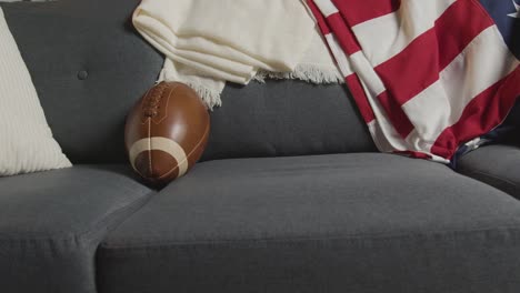 lounge at home of person watching american football game on tv with drinks snacks and ball 1