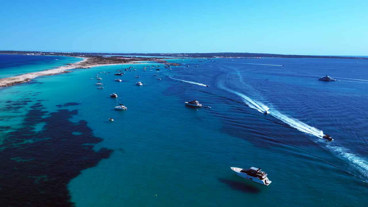 Ibiza Formentera coastline with numerous yachts and boats navigating crystal clear turquoise waters. Perfect aerial view flight descending drone