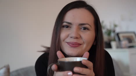 primer plano en cámara lenta de una joven feliz sonriendo sosteniendo una taza en sus manos