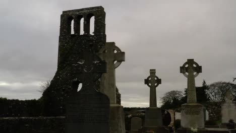 Ground-level-pan-across-old-historic-cemetery-headstones-with-creepy-old-bell-tower-wall