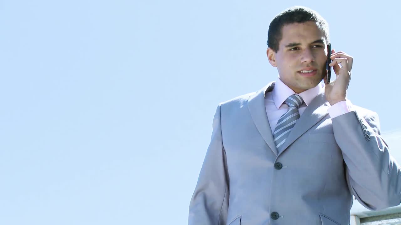 사업가 가 야외 에서 휴대 전화 로 이야기 하고 있다