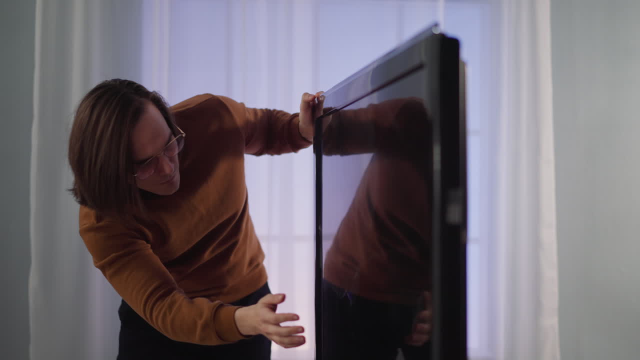 hombre confundido golpea la pantalla de televisión con trincheras en el apartamento