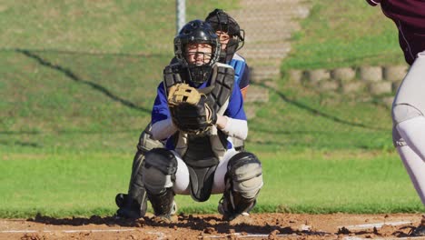 blanke vrouwelijke honkbalspeler in catcher positie die bal vangt op het honkbalveld