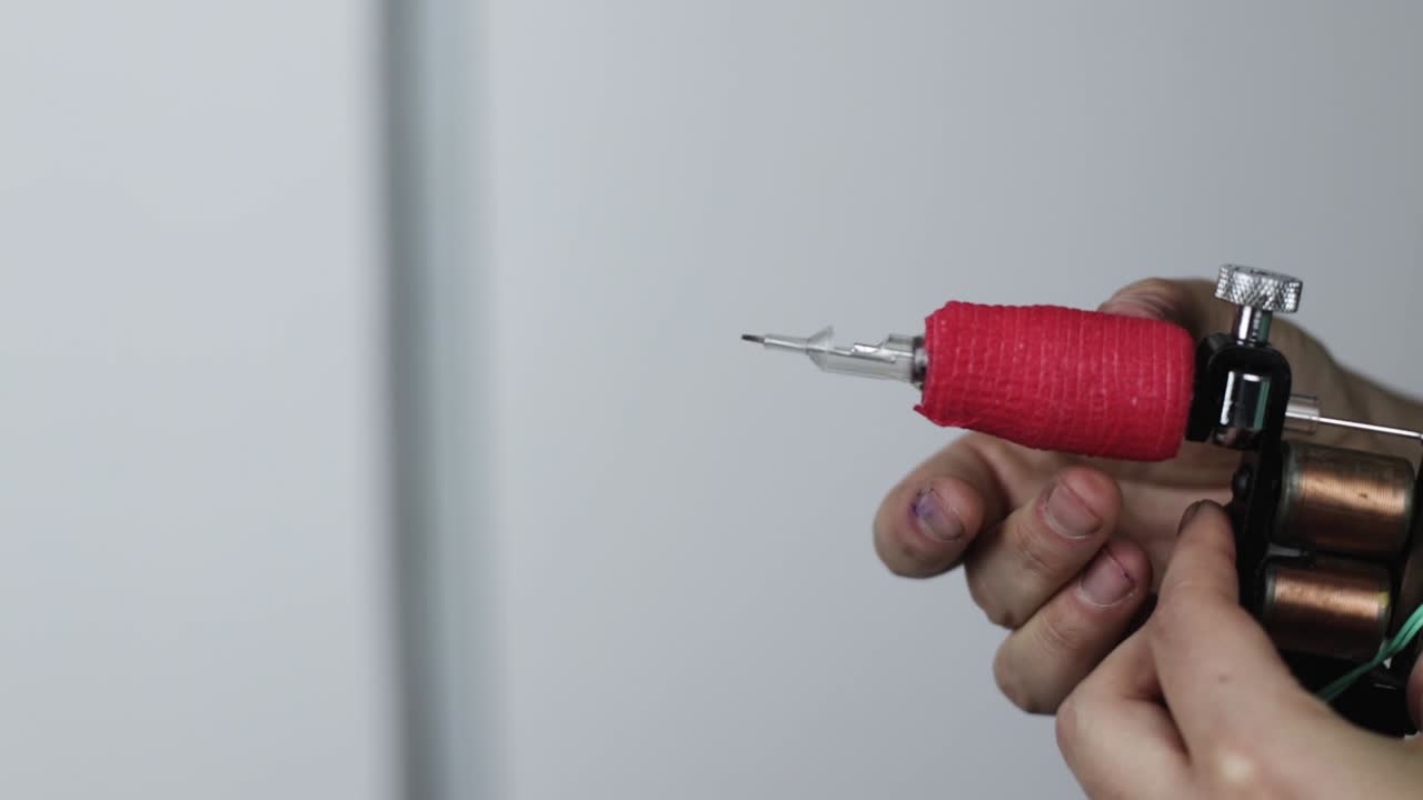 tatuador profesional insertando la aguja en la máquina de tatuaje