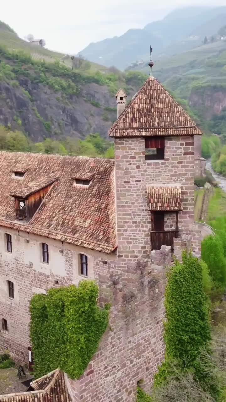 Vertical aerial shot circling around Castel Roncolo during daytime, Bolzano