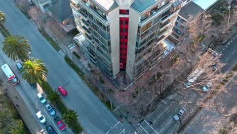 Vista-De-Arriba-Hacia-Abajo-De-Un-Edificio-Con-Ascensor-Rojo-De-Estilo-Retro-Bajando,-Avenida-Libertad,-Tráfico-En-La-Intersección-De-La-Calle