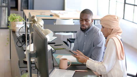 discussing work, colleagues using tablet and laptop in modern office setting