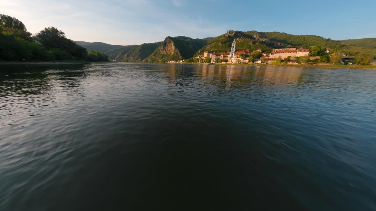Prise de vue basse FPV au-dessus de la surface de l'eau s'approchant du monastère de l'abbaye, Dürnstein, Autriche