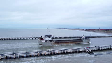 aerial pan right shot of boat entering nieuwpoort port on cloudy day