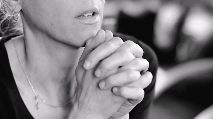 woman praying with hand over her face on grey background with people stock video