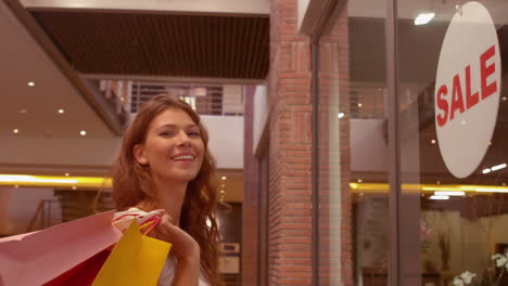 mujer feliz viendo el letrero de venta en la ventana de la tienda