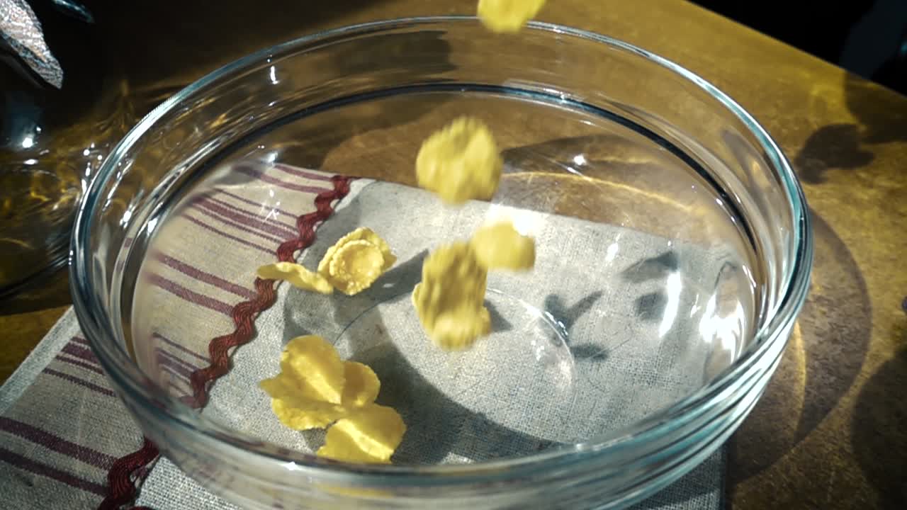 Fiocchi di mais gialli croccanti nella ciotola per una deliziosa colazione mattutina con latte. Slow motion con ripresa rotatoria.