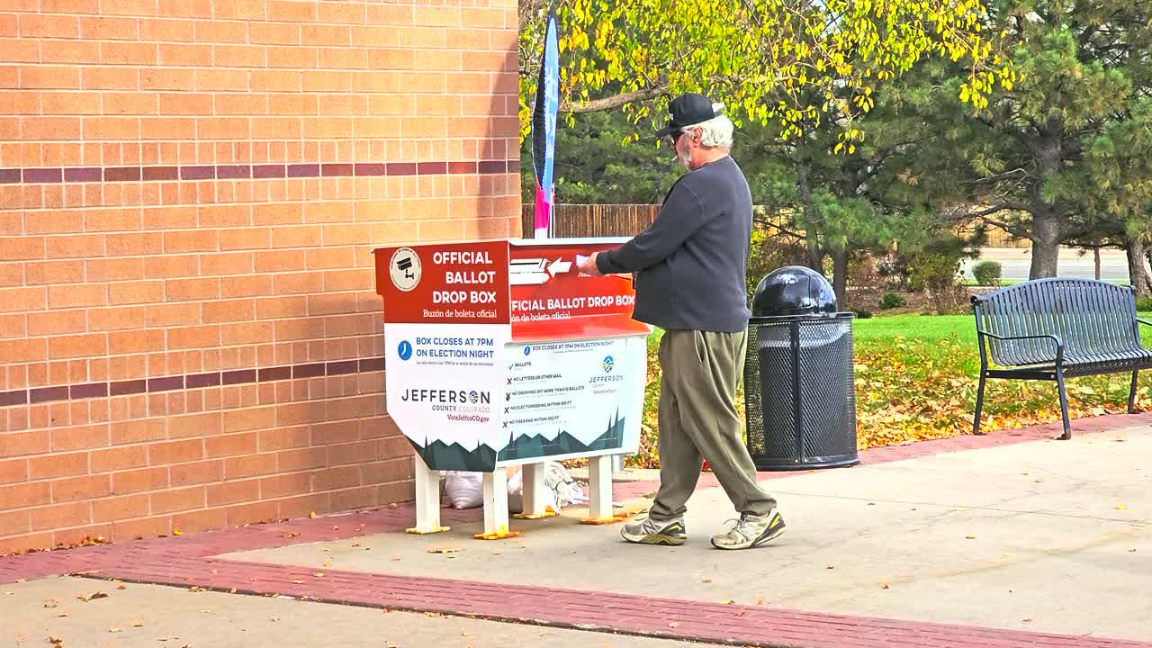 A man votes by placing his mail-in ballot envelope into an official drop box, symbolizing civic duty, democracy, safety, election integrity, inclusivity, and the importance of secure participation