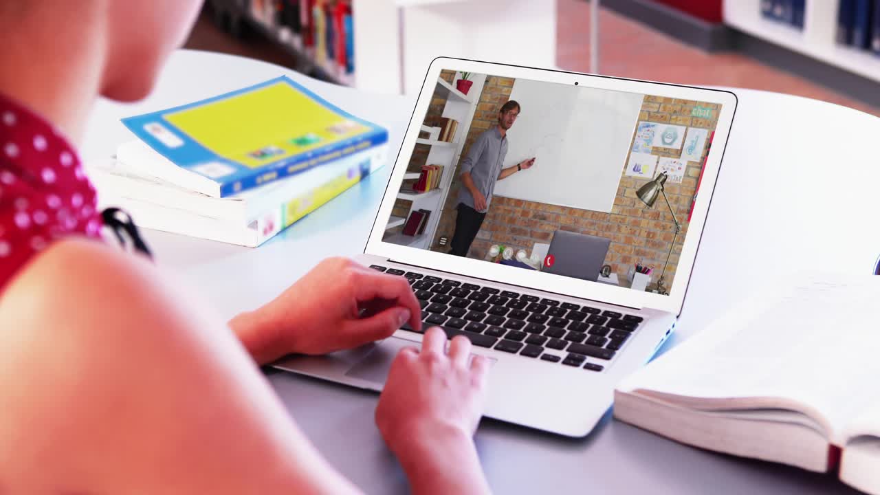 estudiante caucásica usando una computadora portátil en una videollamada con un profesor masculino