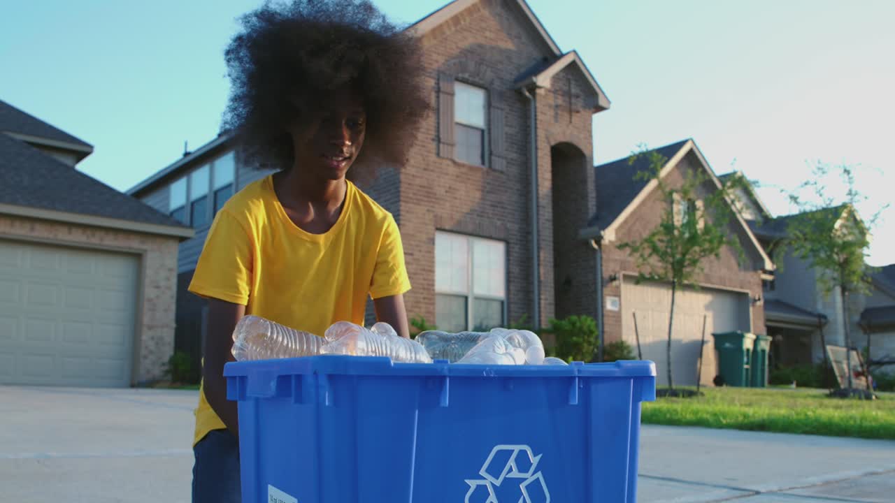 African American adolescence placing plastic bottles in recycle bin