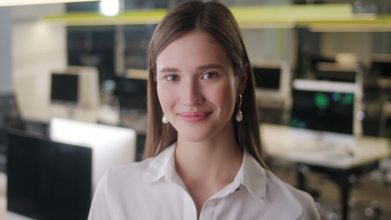 retrato de una hermosa mujer joven con camisa blanca mirando hacia la cámara y sonriendo encantadoramente. mujer exitosa trabajando en una oficina de espacio abierto