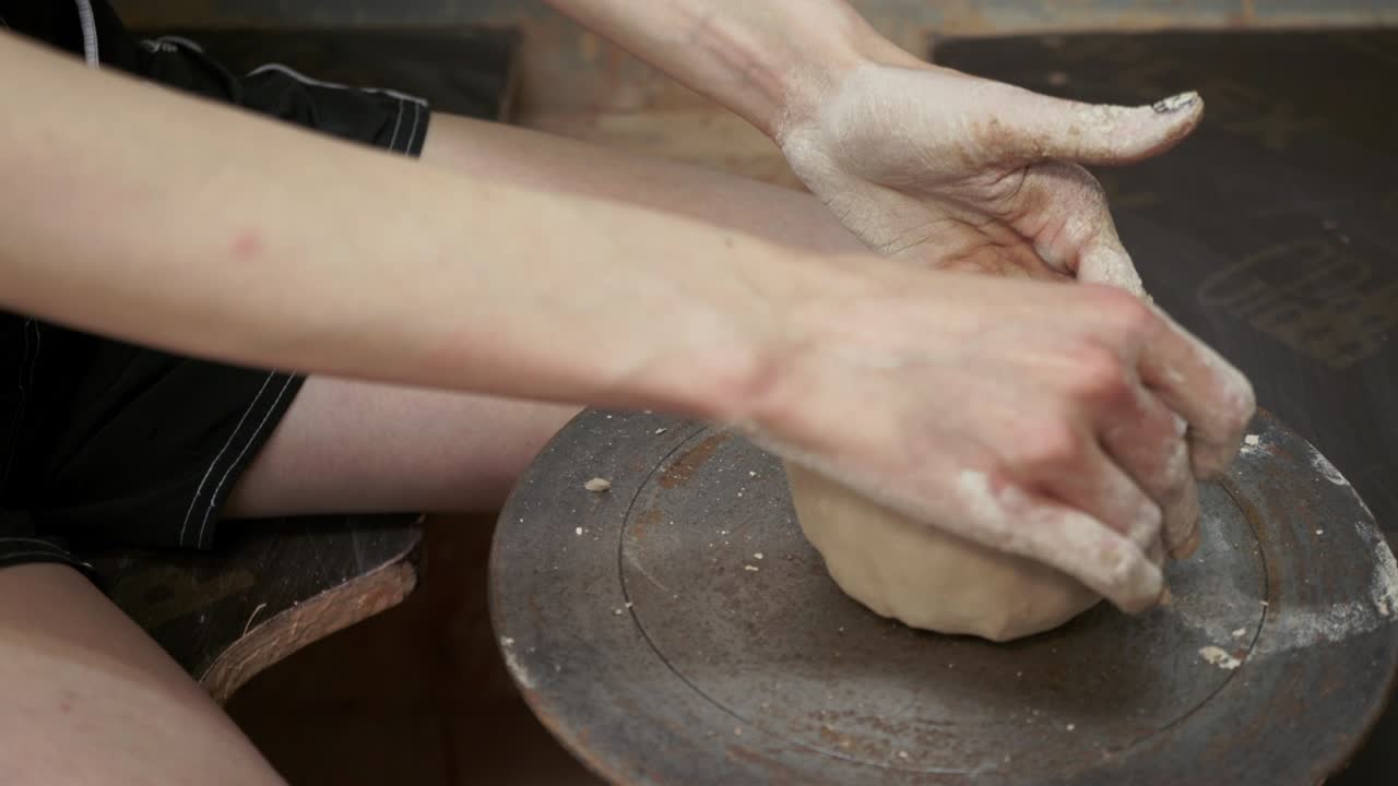若い女性が粘土で水差しを作る。女性の手が陶器を形作る。
