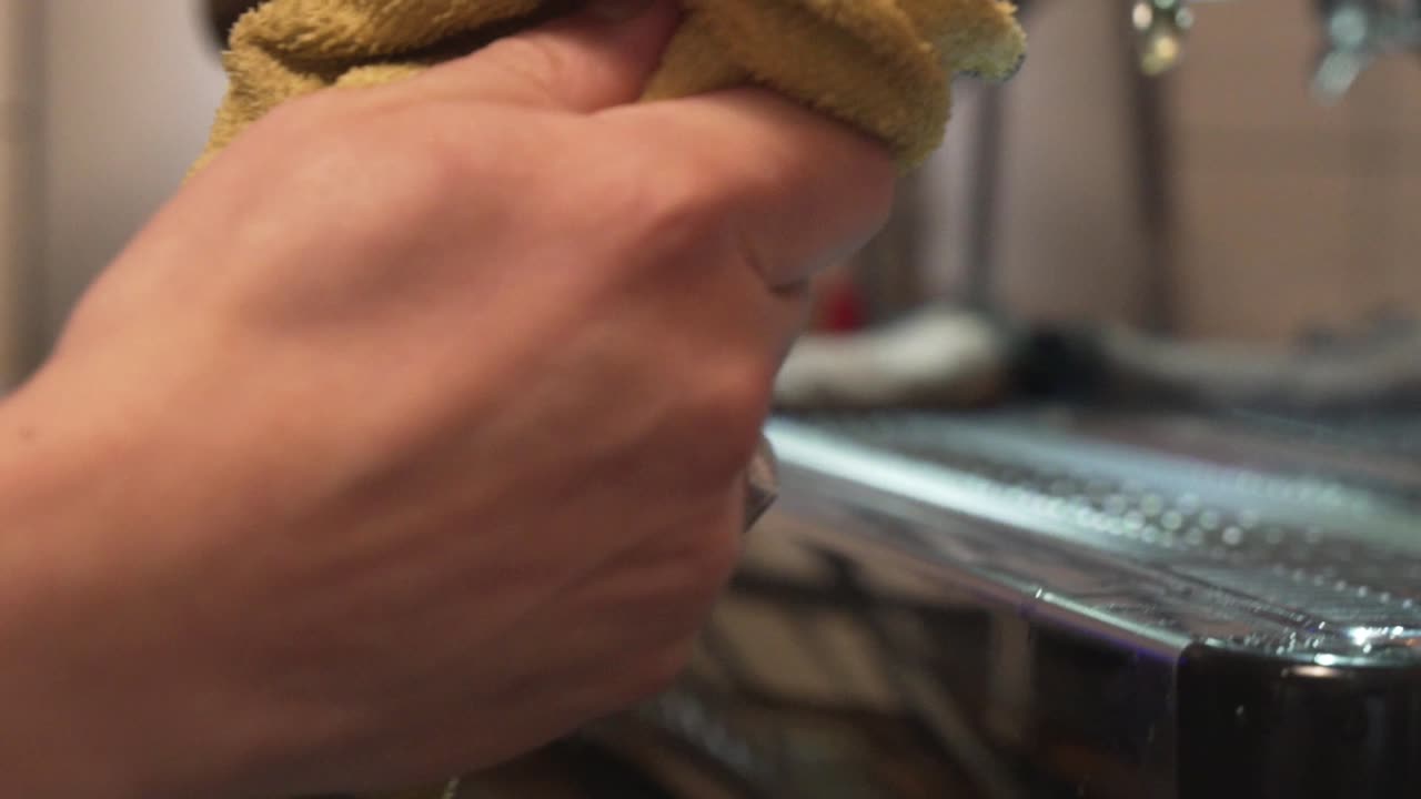 barista limpia la varilla de vapor de la máquina de café después de espumar la leche