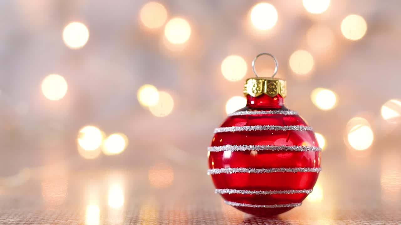 luces de navidad parpadeantes detrás de un ornamento de navidad rojo brillante