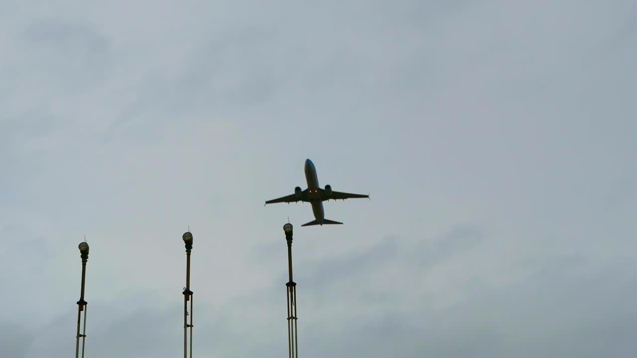 замедленная съемка пролета самолета над аэронавигационными огнями на фоне серого неба