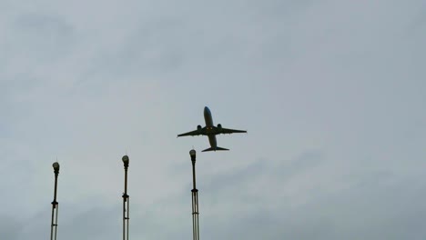 Cámara-Lenta-De-Un-Avión-Que-Pasa-Sobre-Luces-Aeronáuticas-Con-Un-Cielo-Gris