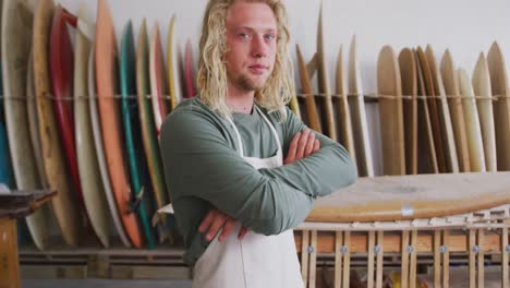 hombre caucásico fabricante de tablas de surf con un delantal protector con los brazos cruzados