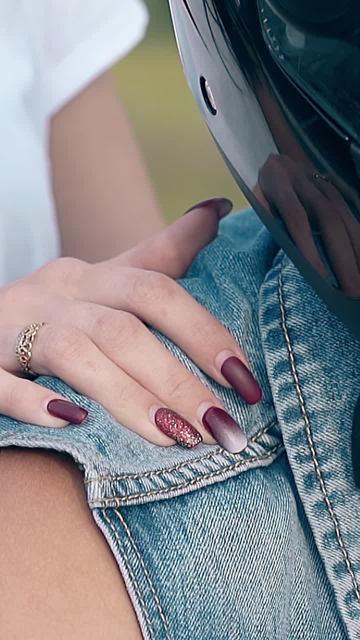 close view girl hand with red manicure and golden ring holds man in blue denim vest shoulder