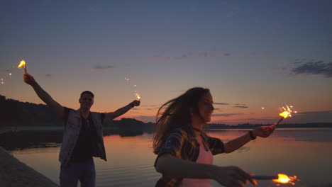 los jóvenes amantes, hombre y mujer, corren alegremente a lo largo de la playa con escamas calientes en sus manos a cámara lenta. relación romántica. las escamas arden en las manos de los amantes.