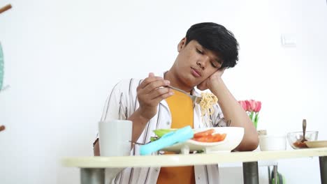 asian young man eating noodle with no appetite