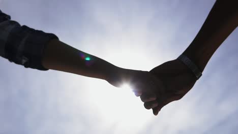 Low-angle-view-of-unrecognisable-romantic-couple-starting-to-hold-hands-as-they-stand-together-and-then-separating-them