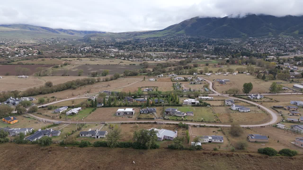 vuelo de drone de dolly del área de construcción, ciudad de tafi del valle con la montaña nublada en el fondo, aérea en cámara lenta