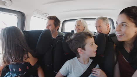 multi generation family sitting in back of people carrier being driven to vacation