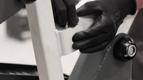 worker's hands in gloves inserting flat washer and bolt to secure metal structure - assembling fabricated metal