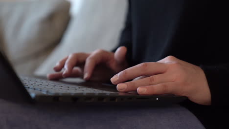 Closeup-shot-of-a-woman's-hands-using-a-laptop-on-her-lap