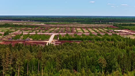 extensive peat field with green strips and brown extraction rows surrounded by forest