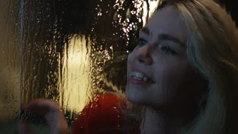 woman looking through a rainy window at night