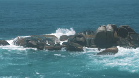slow-motion-shot-of-waves-crashing-against-a-stack-of-rocks-in-Tayrona-park,-Colombia