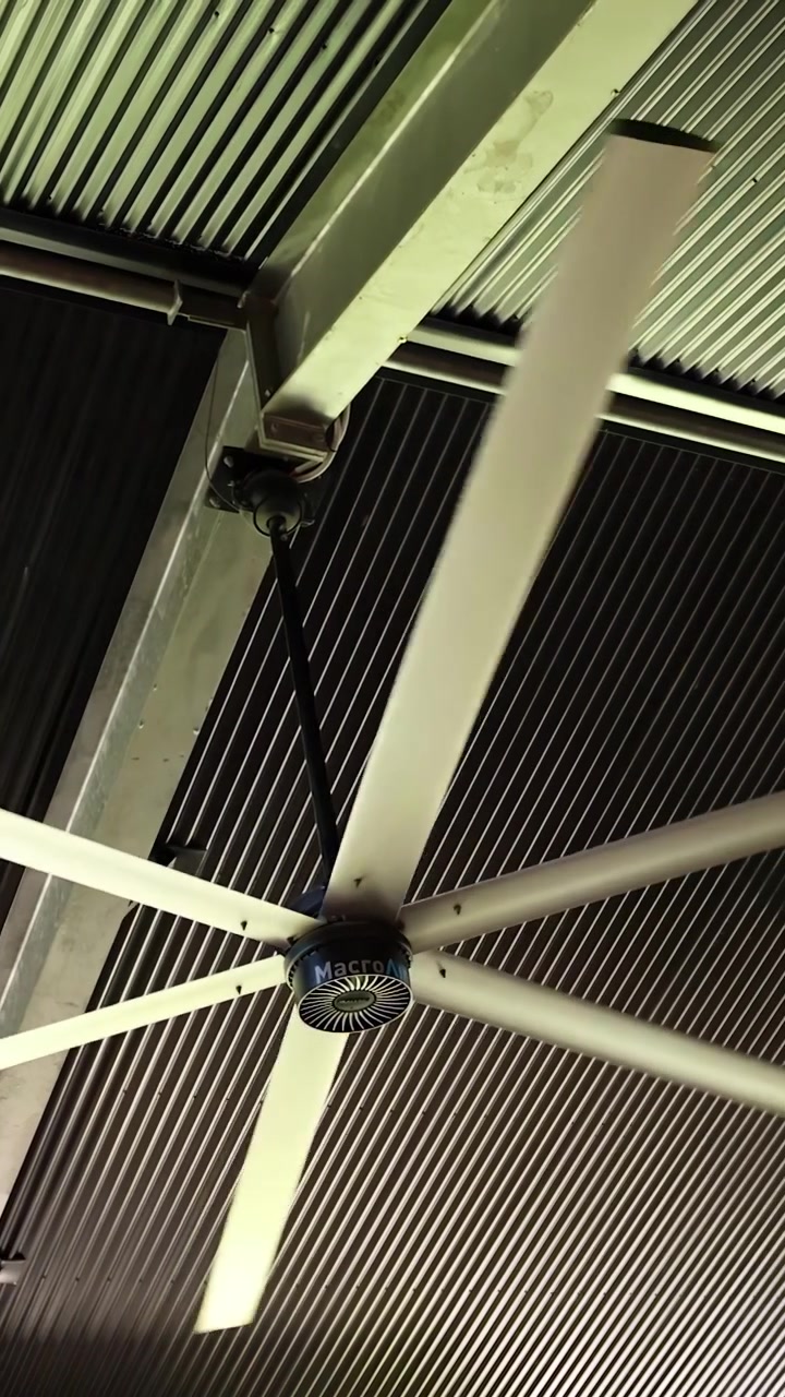 Lavvinkelbillede af en stor industriventilator, der snurrer mod et bølgeblikloft.